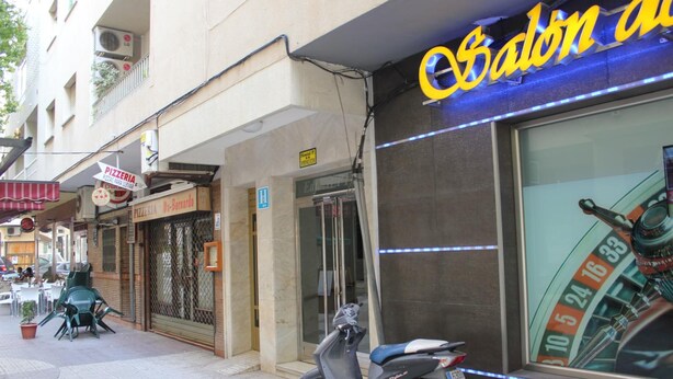A storefront with a sign for a pizzeria and a salon. - Hostal Andalucía (Almunecar)