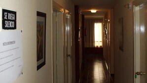 A hotel hallway with a sign that reads "SE RUEGA SILENCIO" and a door with a green handle. - Hostal Andalucía (Almunecar)