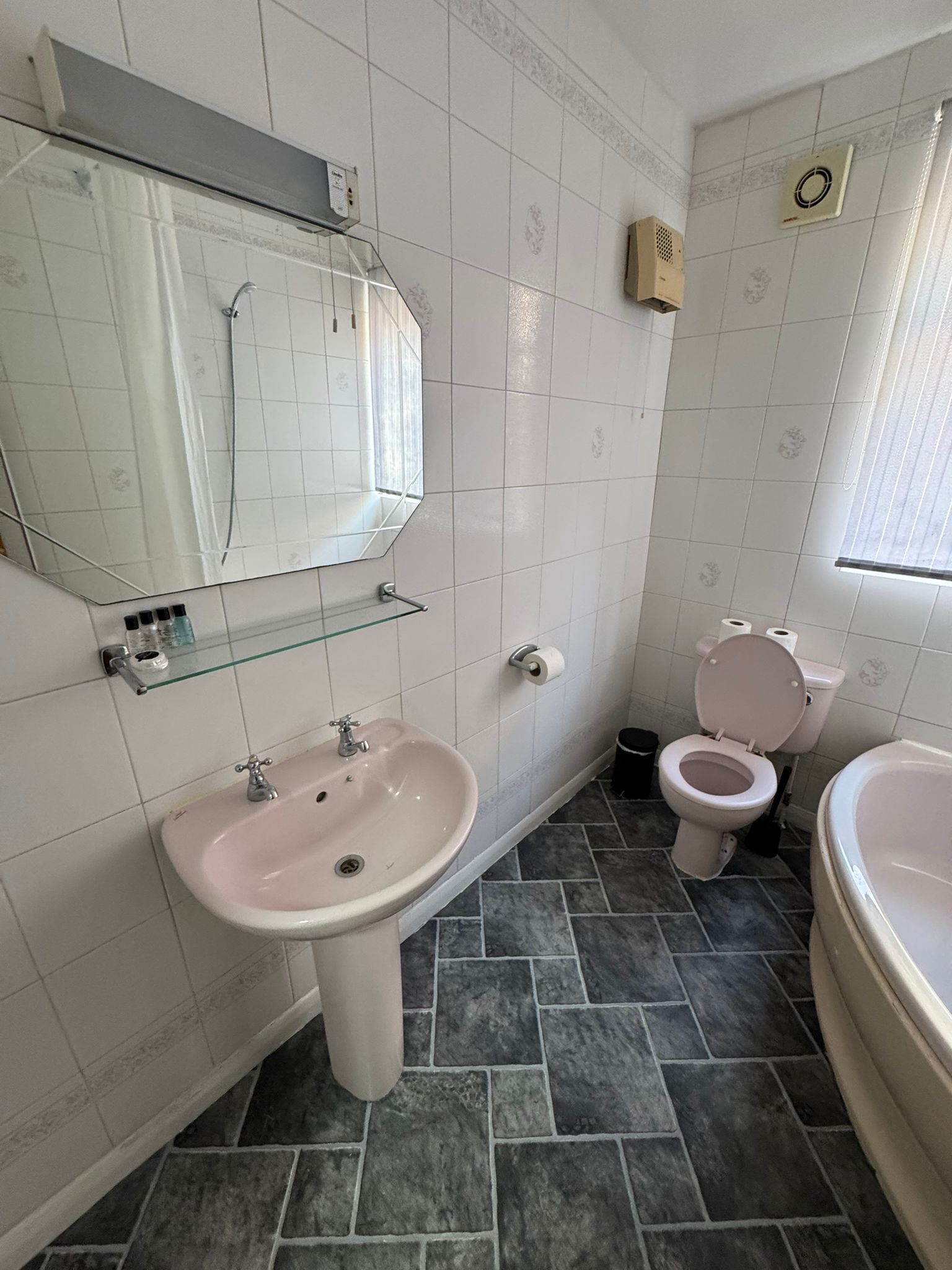 A bathroom with a sink, mirror, toilet, and bathtub.