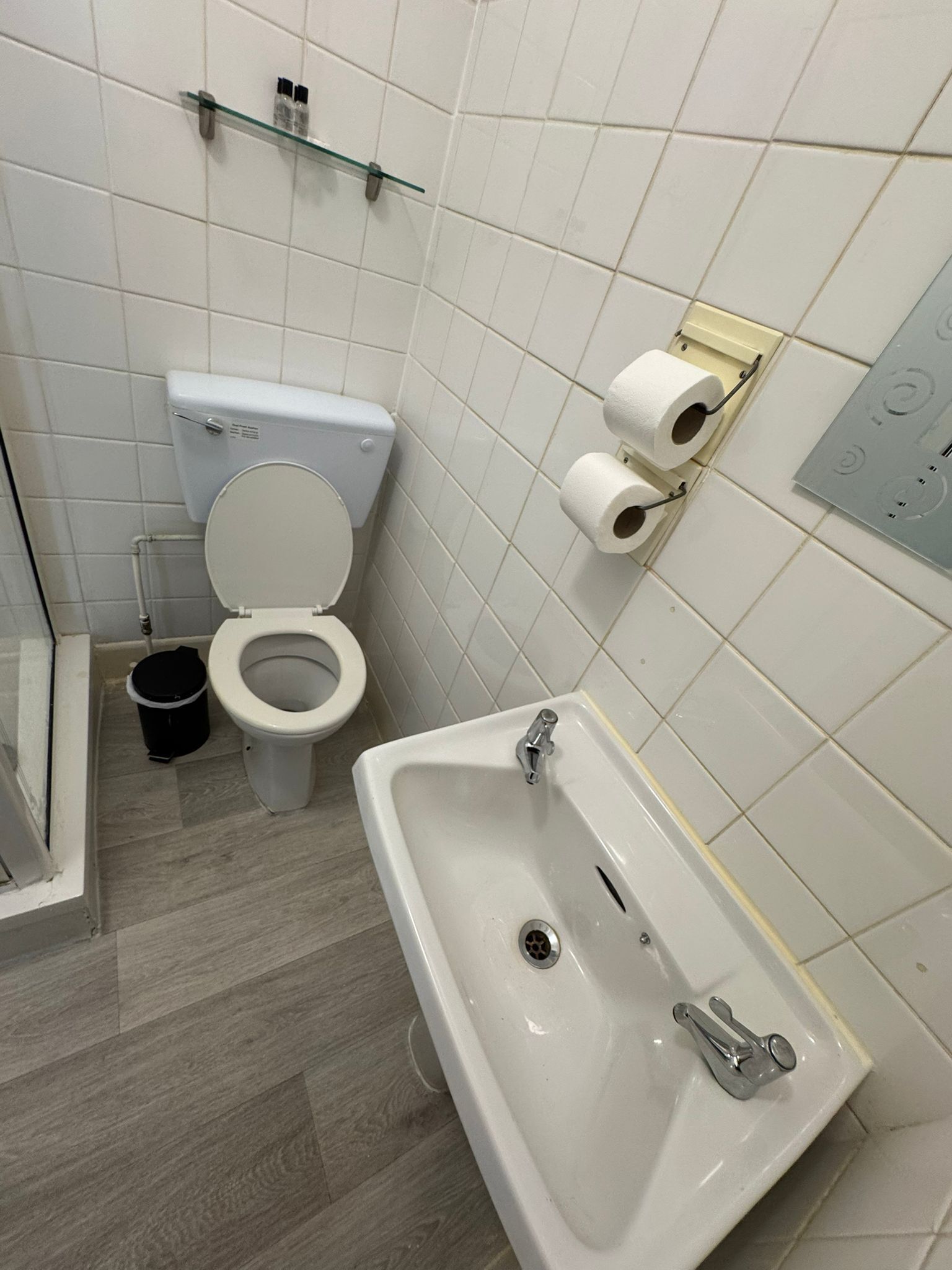 A bathroom with a toilet, sink, and a trash bin.