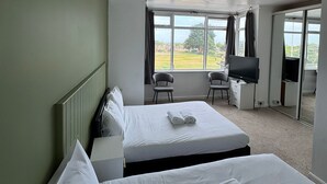 A hotel room with two beds, a television, and a view of the outdoors. - Sea Side Hotel (Skegness)