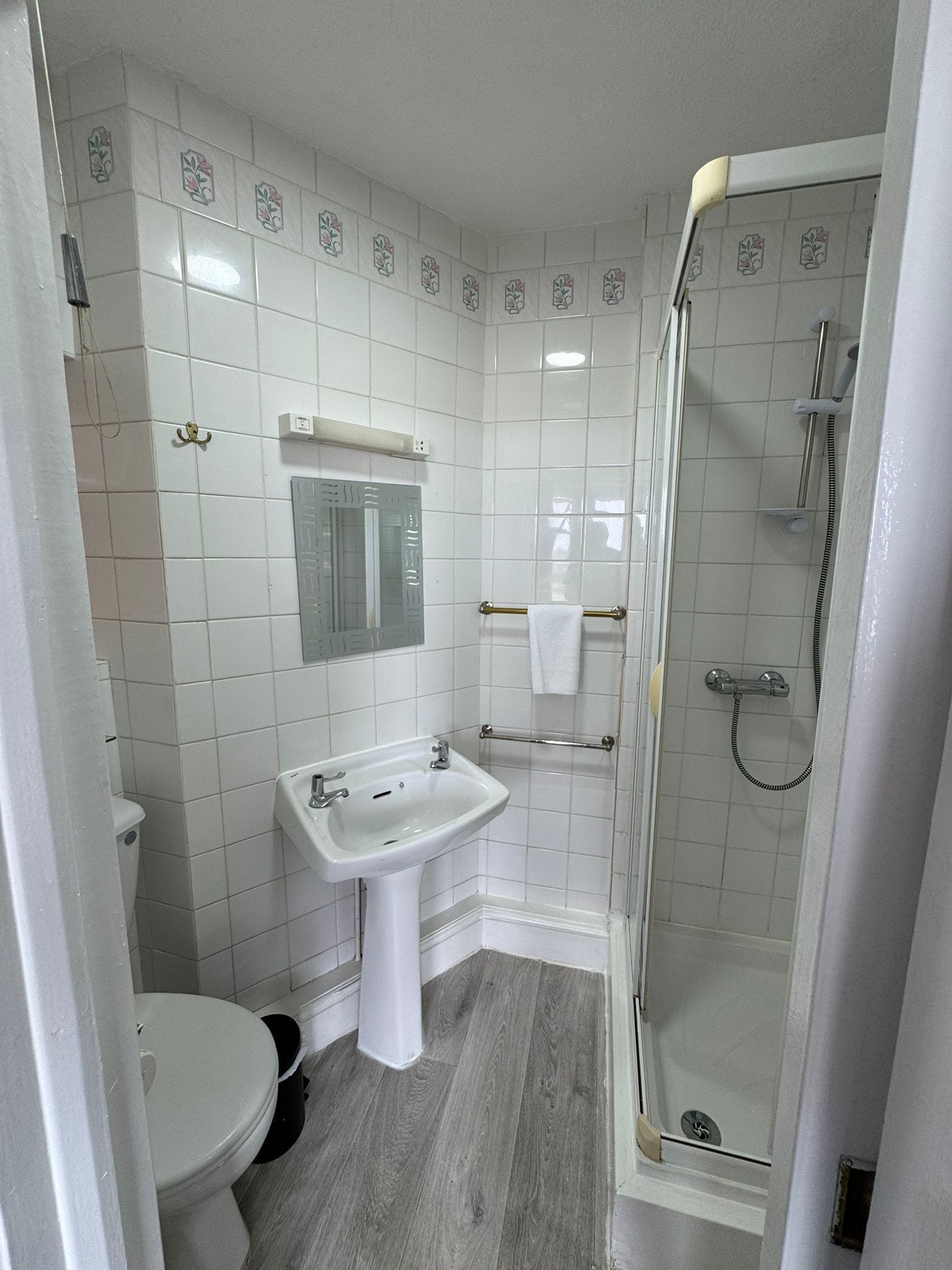 Un baño con azulejos blancos, un lavabo, un inodoro y una ducha.