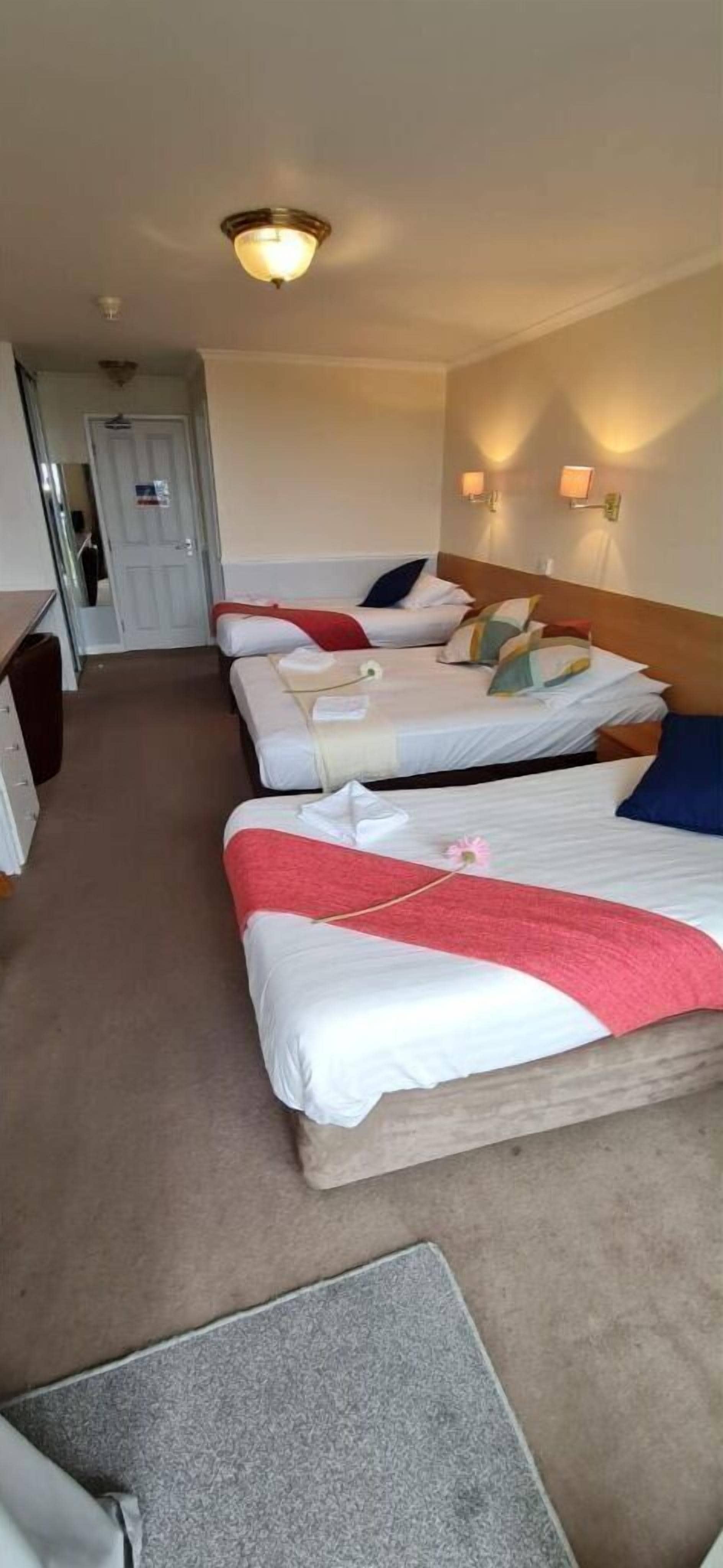 Ein Hotelzimmer mit zwei Betten, einem Schreibtisch und einer Tür.