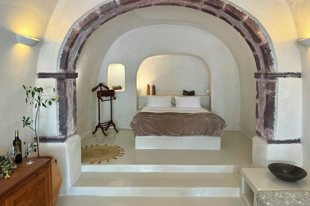 Un dormitorio con cama, mesita de noche, espejo y ventana.