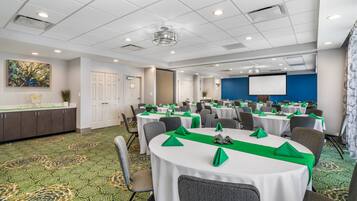 A conference room with round tables, chairs, and a projector screen.
