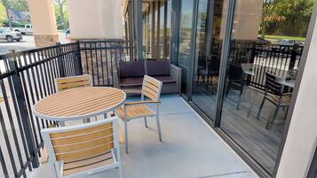 An outdoor seating area with a round table and chairs, a sofa, and a glass railing.