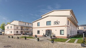 A modern building with a flat roof and a sign reading "TRIO". - TRIO Apartment Hotel Berlin (Berlin)