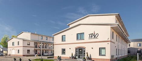 A modern building with a flat roof and a sign reading "TRIO".