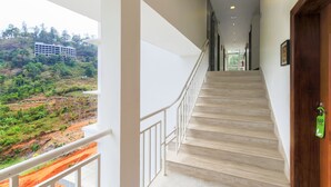 Una escalera conduce a un balcón con vistas a un edificio y follaje.