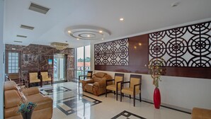 Un hall con mostrador de recepción, zona de estar y una pared decorativa.