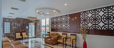 Un hall con mostrador de recepción, zona de estar y una pared decorativa.