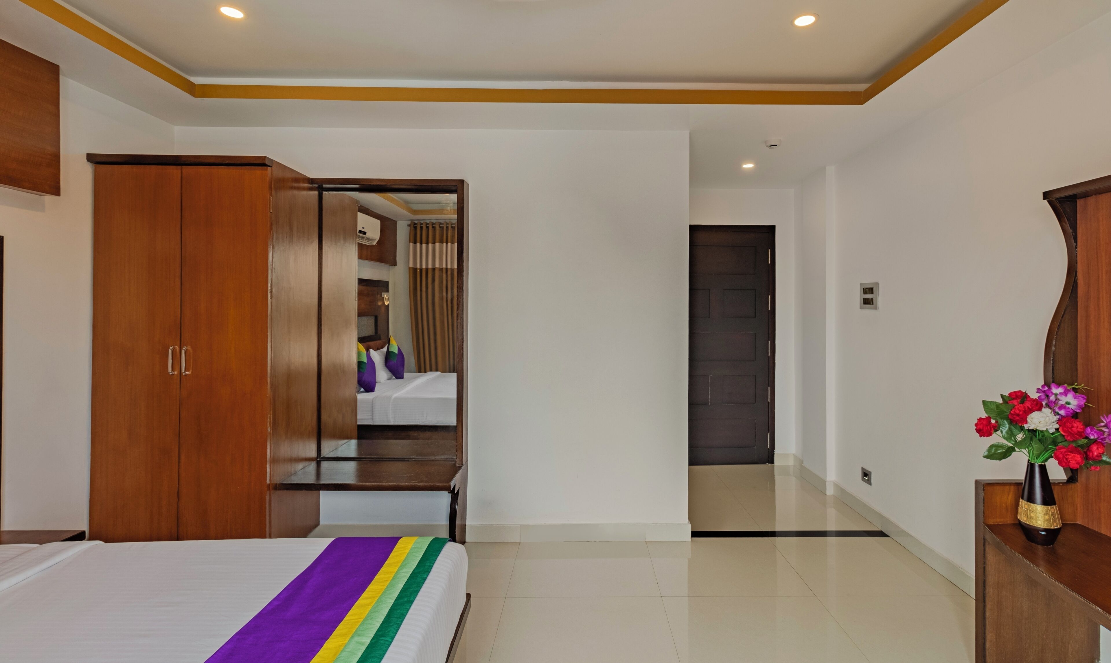 A hotel room with a bed, wooden wardrobe, and a desk.