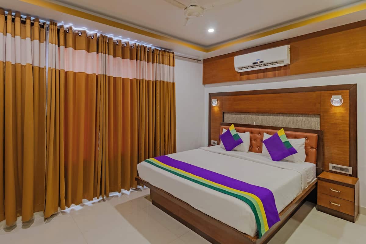 Una habitación de hotel con una cama grande, cabecera de madera y ventilador de techo.