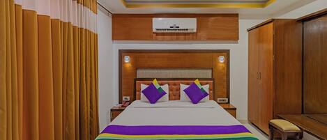 Una habitación de hotel con una cama grande, cabecera de madera y un armario.
