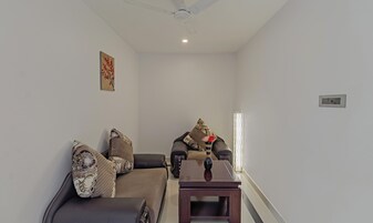 Una sala de estar con un sofá, dos sillones, una mesa de centro y un ventilador de techo.