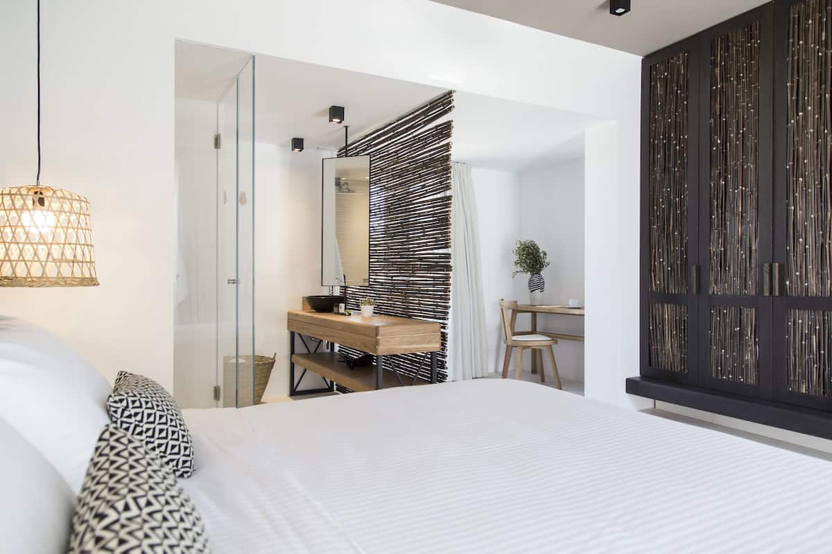 Une chambre à coucher moderne avec un grand lit, un bureau en bois, un miroir et un panneau décoratif mural.