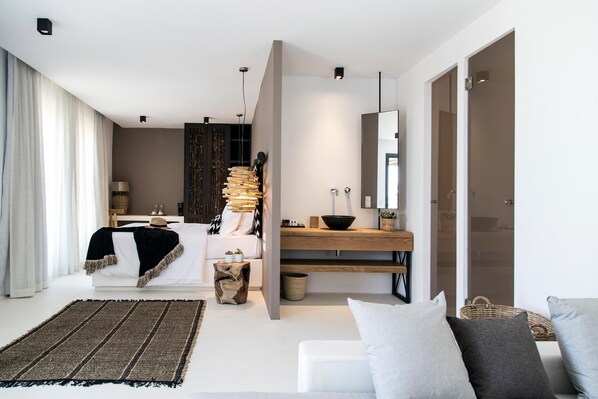 A modern bedroom with a bed, bedside table, and a large mirror. - My Mykonos Hotel by Mr and Mrs White (Mykonos)