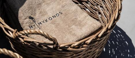 Una cesta de mimbre con un cojín color beige, con la etiqueta 'MY MYKONOS'.