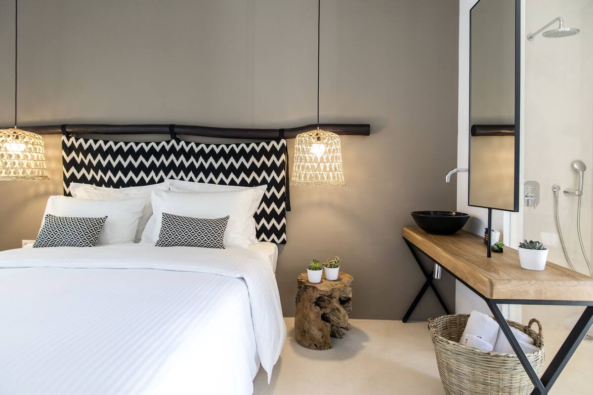 Une chambre à coucher moderne avec un lit, des lampes de chevet, une table de chevet en bois, un miroir et une petite plante en pot.