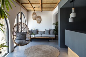 A modern living room with a hanging chair, a sofa, and a round rug. - My Mykonos Hotel by Mr and Mrs White (Mykonos)