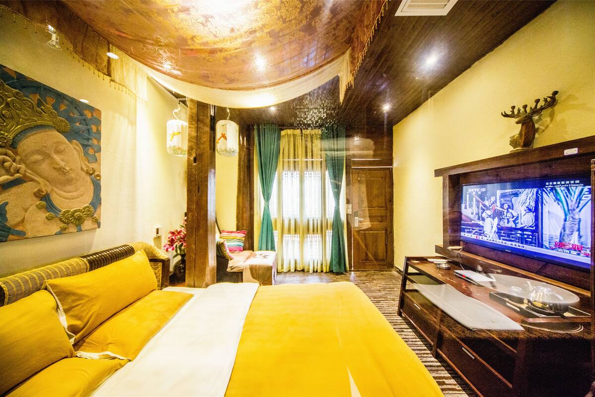 A hotel room with a bed, a television, and a painting on the wall.
