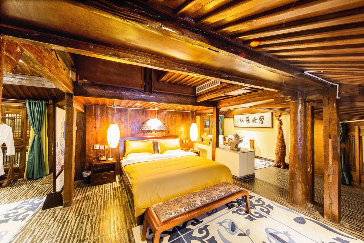 A traditional wooden room with a bed, a bench, and a small table.