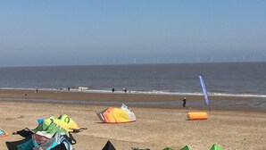 A beach with multiple kites and a wind turbine in the background. - The Sherwood (Skegness)