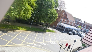 A parking area with marked spaces, a pedestrian crossing, and a building with a covered entrance. - The Sherwood (Skegness)