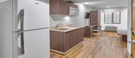 Una cocina compacta con un refrigerador blanco, armarios de madera, un microondas integrado y una ventana con vistas.