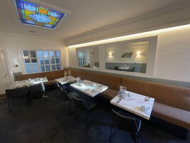 Un restaurante con cabinas y mesas, un vitral y un espejo grande en la pared.