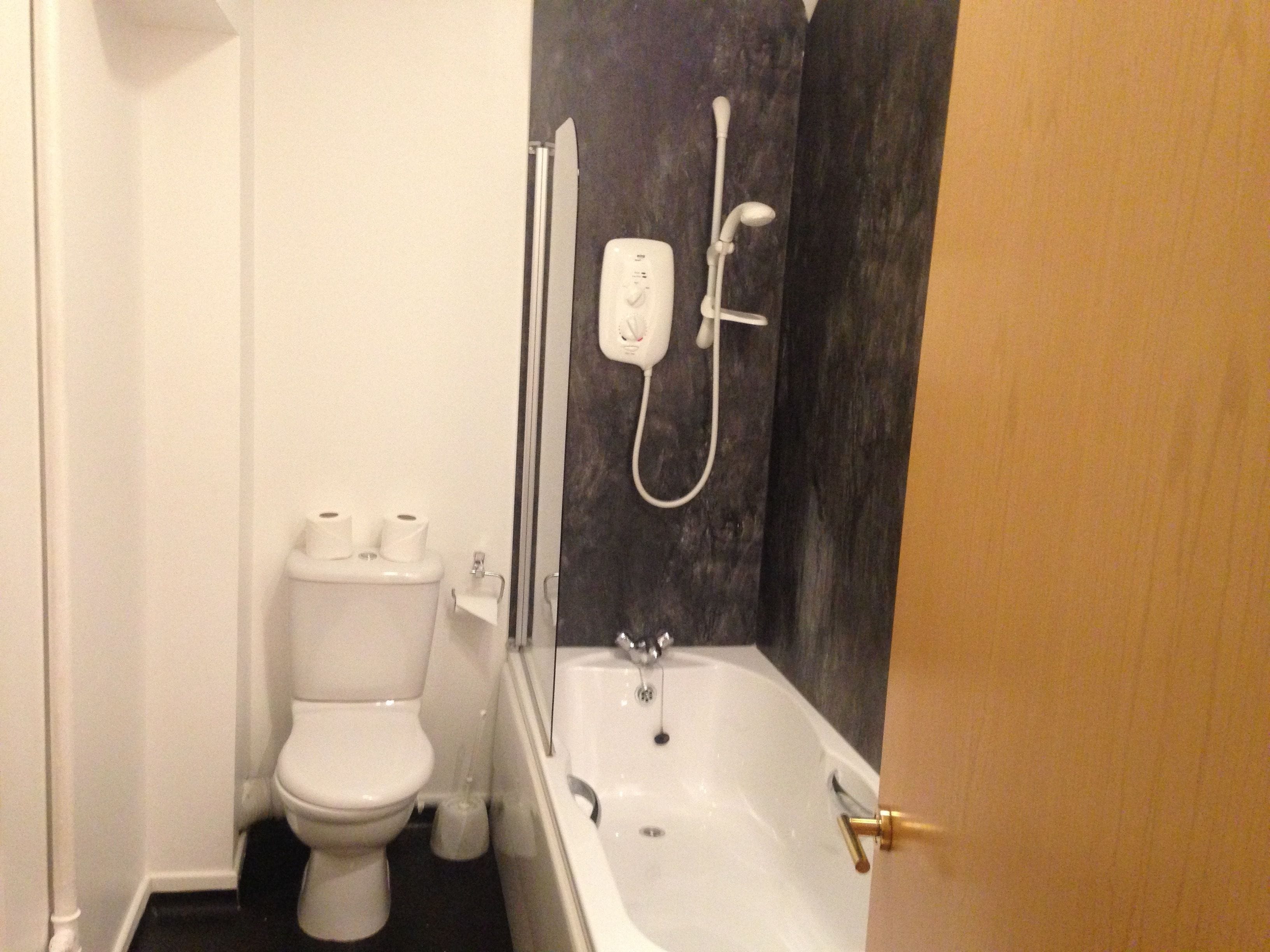 Un baño pequeño con inodoro, ducha y bañera.