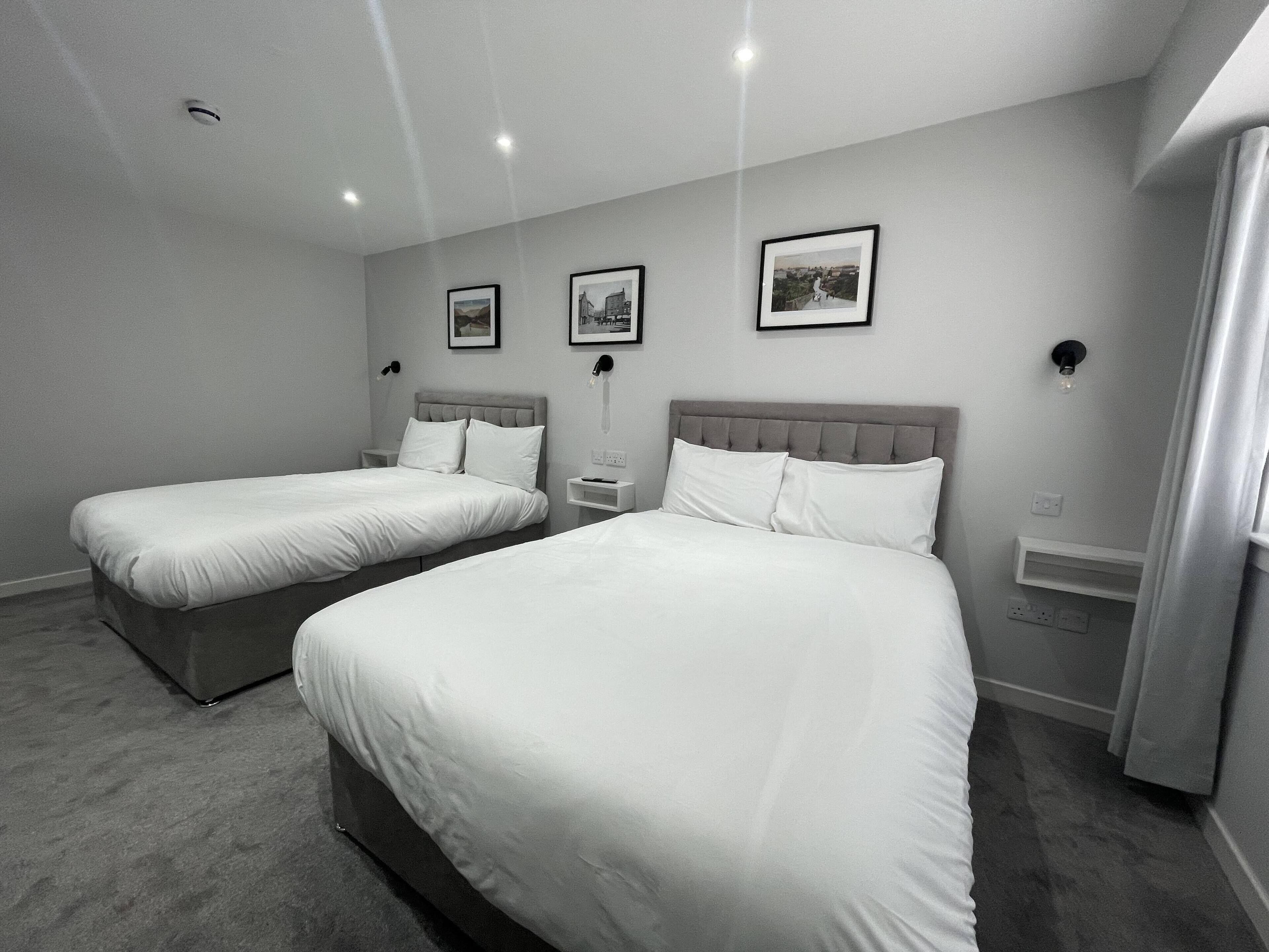Une chambre d’hôtel moderne avec deux lits simples, une décoration aux couleurs neutres et un aménagement simple.