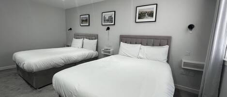 Une chambre d’hôtel moderne avec deux lits simples, une décoration aux couleurs neutres et un aménagement simple.