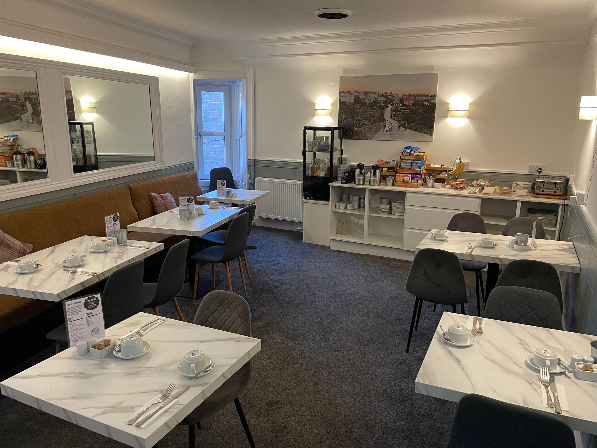 Un espace repas doté de tables en marbre, de sièges rembourrés et d’un buffet proposant une variété de plats et de boissons.
