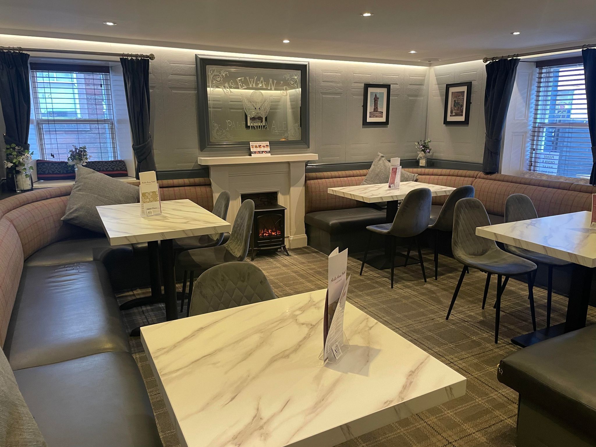 A restaurant with a fireplace, booths, and tables.