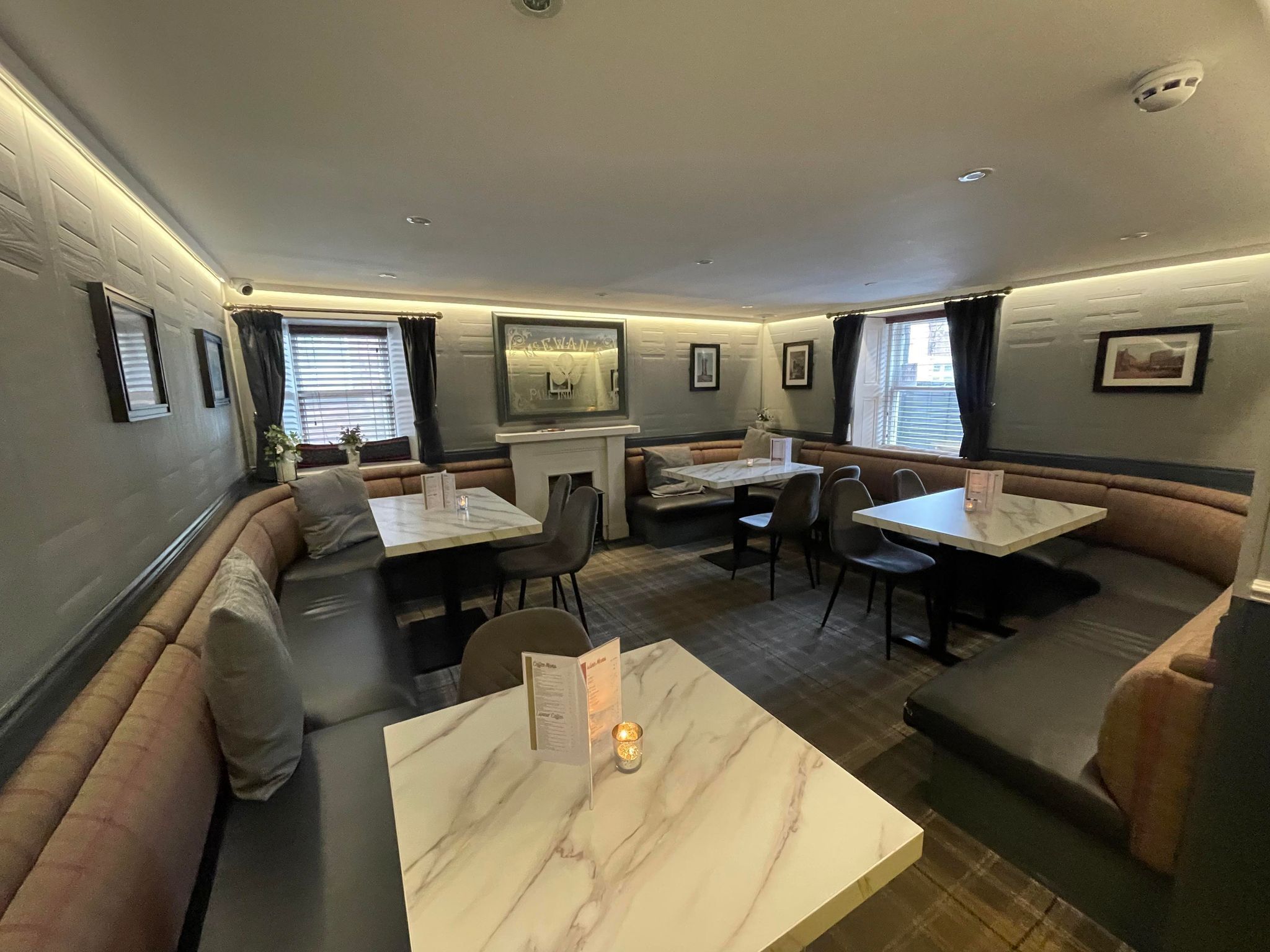 A restaurant with booth seating, marble tables, and framed pictures on the walls.