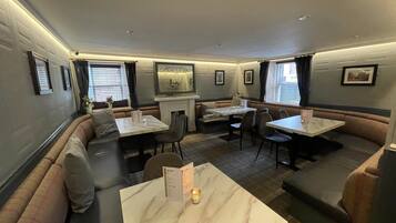 A restaurant with booth seating, marble tables, and framed pictures on the walls.