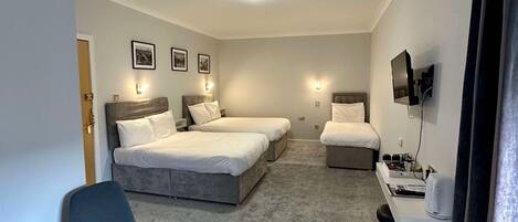 A hotel room with two beds, a desk with a computer, a chair, and a television mounted on the wall.