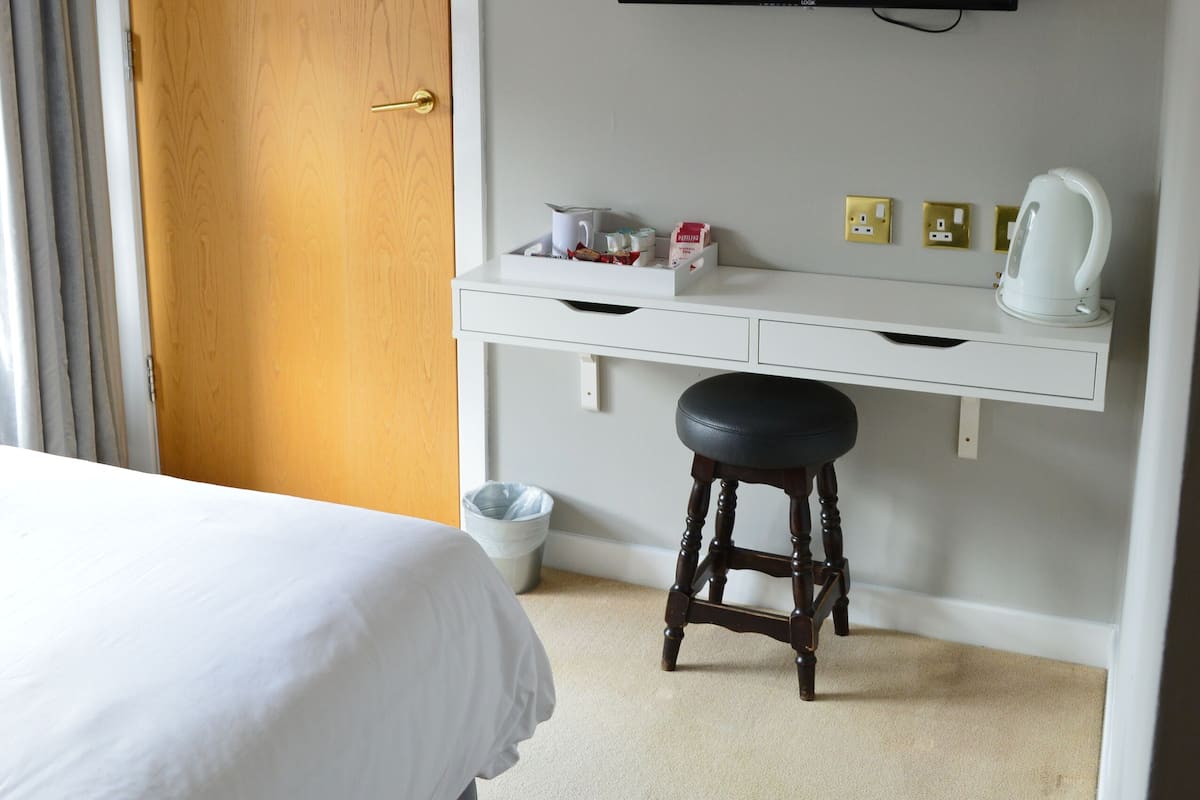 Ein Hotelzimmer mit Bett, Schreibtisch mit Stuhl, Fernseher und Tür.