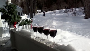 A snowy outdoor area with a railing and four wine glasses filled with red wine. - Golden Stage Inn B&B (Cavendish)