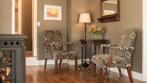 A room with two patterned chairs, a table with a lamp, a mirror, and a framed picture on the wall. - Golden Stage Inn B&B (Cavendish)