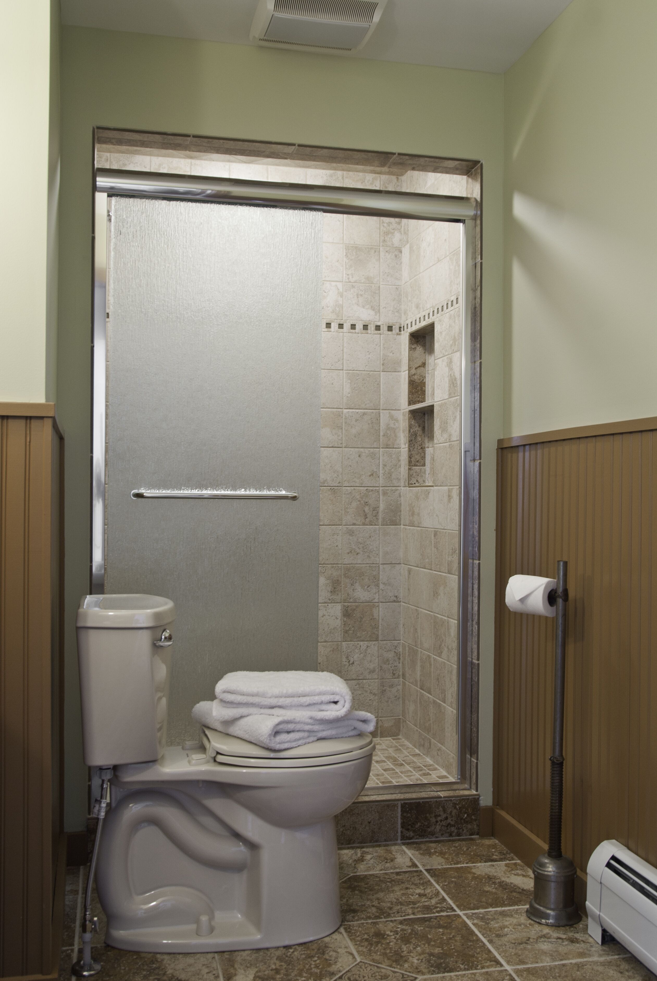 A bathroom with a shower, toilet, and towel rack.