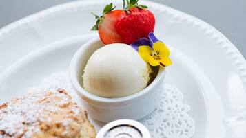 A dessert plate with a scoop of vanilla ice cream, a strawberry, and a flower.
