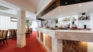 Un hall de hotel con mostrador de recepción, zona de estar y bar.