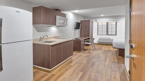 Una cocina compacta con un refrigerador blanco, armarios de madera, un microondas integrado y una ventana con vistas.