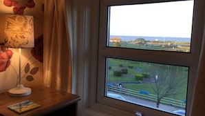A room with a large window overlooking a park and a body of water. - Balmoral (Skegness)