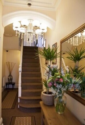A staircase leading to a second floor, flanked by a mirror and potted plants. - Balmoral (Skegness)