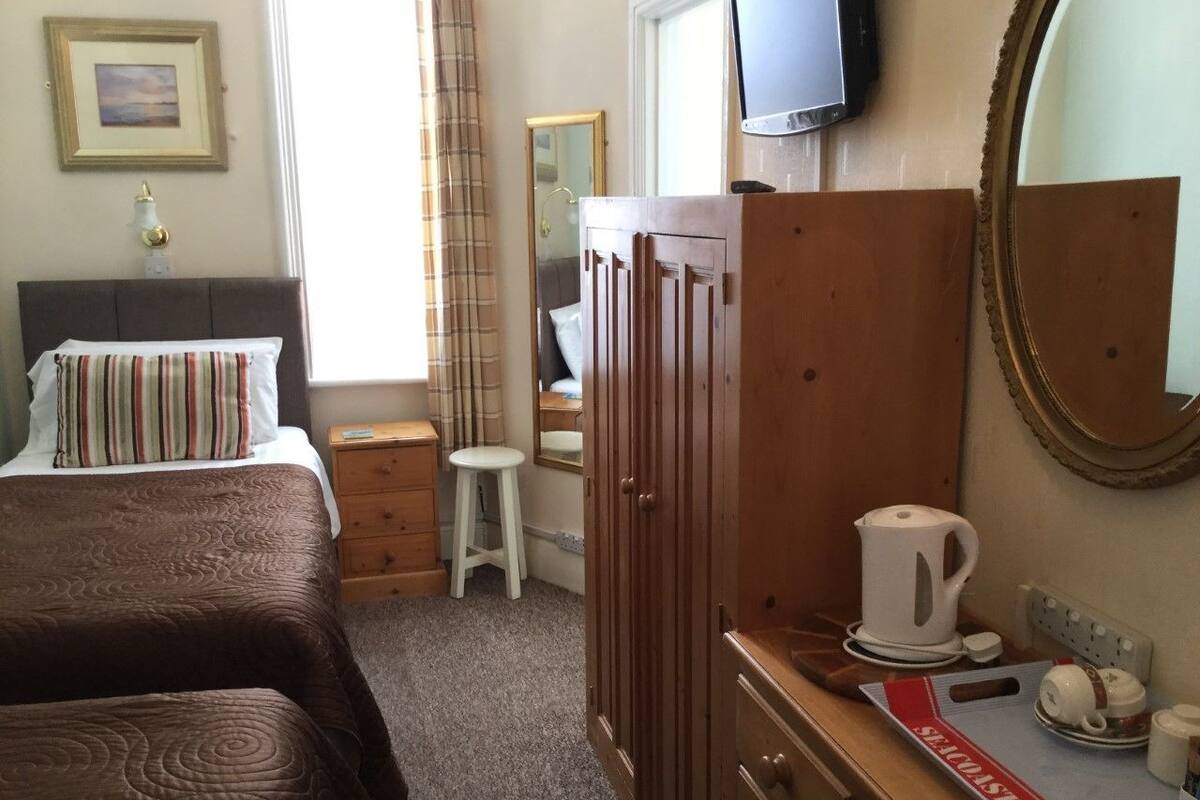 A hotel room with two beds, a wooden dresser, a television, and a mirror.