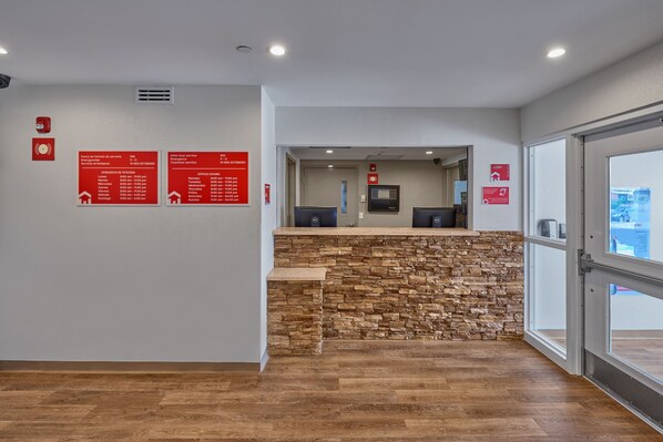 A reception area with a stone accent wall, wooden flooring, and red informational signs on the wall.