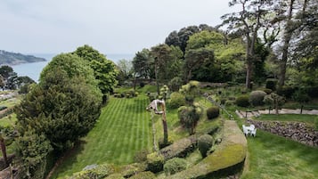 A well-manicured garden with a variety of trees and shrubs, a neatly trimmed lawn, and a stone wall.